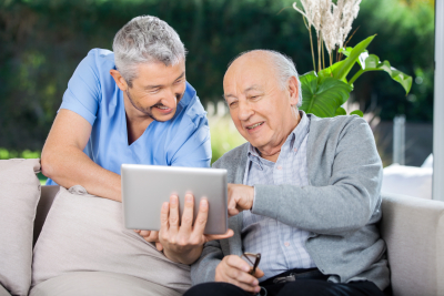 male nurse and senior man smiling while using tablet computer